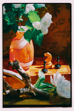 A Vase of White Jasmine Flowers and a Chess 