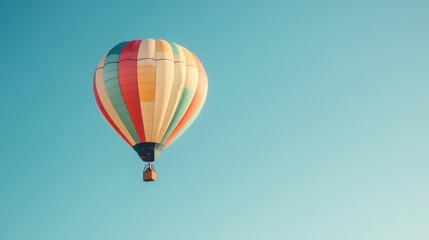 Naklejka premium Colorful Hot Air Balloon Ascending Against a Blue Sky