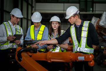 Factory engineers inspect on machine. Confident team mature businessman with laptop standing by robotic arm in industry businessman inspect at height technology for produce the electronic part device.