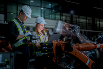team engineers inspecting on machine with smart tablet. Worker works at heavy machine robot arm. The welding machine with a remote system in an industrial factory. Artificial intelligence concept.