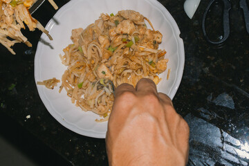 Person eating pad thai 