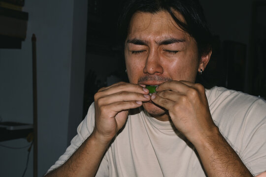 Person eating lemon with sour face 