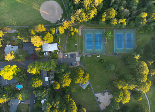 A park with a tennis court and a few houses in the background