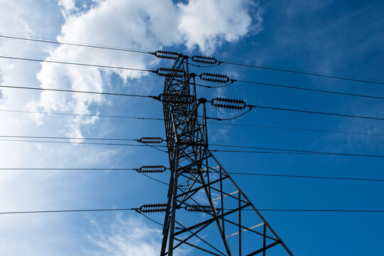 Power tower against blue sky with clouds