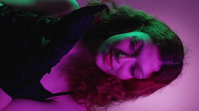 Vertical video. Evil woman. Cunning smile. Pretty glamour female scheming rub hands black gloves evening dress think revenge sneaky plan neon green violet gradient.