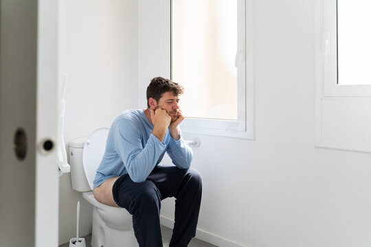 Man sitting on toilet in bathroom