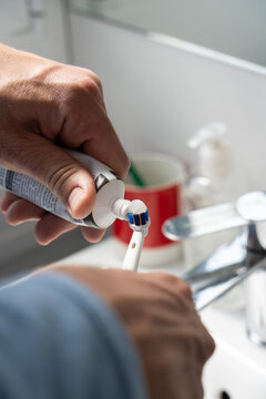 Man Applying Toothpaste to Electric Toothbrush

