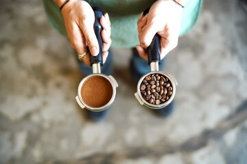 Barista holding ground coffee and beans in portafilter holder against background. Close up.