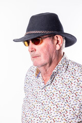 A stylish older gentleman exudes confidence in a chic hat and trendy sunglasses, making a bold outdoor statement
