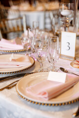 Beautifully set table with plates and clear glasses in a restaurant. Guest table number three in a restaurant. Vertical photo of a reserved table in a cafe or restaurant