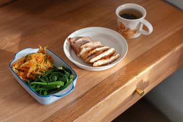 A healthy lunch for a Chinese worker in Asia, featuring grilled chicken and pork with potatoes, choy sum, and other vegetables, all illuminated by natural sunlight, making the meal appear very appetiz