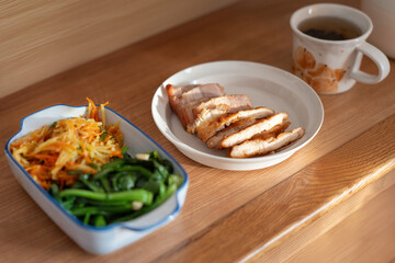 A healthy lunch for a Chinese worker in Asia, featuring grilled chicken and pork with potatoes, choy sum, and other vegetables, all illuminated by natural sunlight, making the meal appear very appetiz