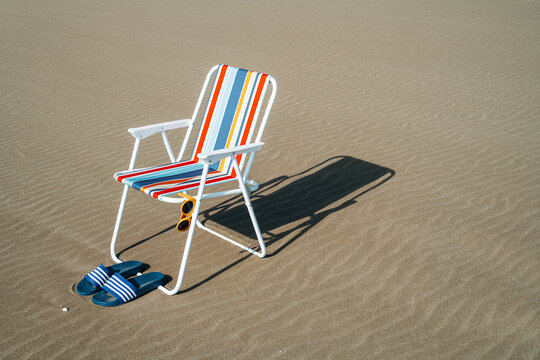 sandals, sunglasses and folding chair on the sand