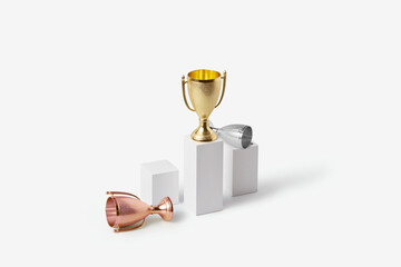 Winner gold cup standing on stand while silver and bronze lying near