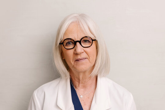 Portrait of senior female doctor in white coat with gray hair