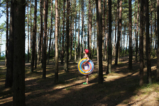 Woman Holding A Colorful Inflatable Ring In A Pine Forest