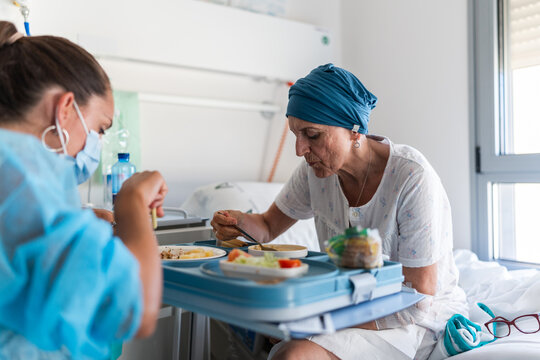 Nurse wearing surgical mask assisting hospital patient eating lunch