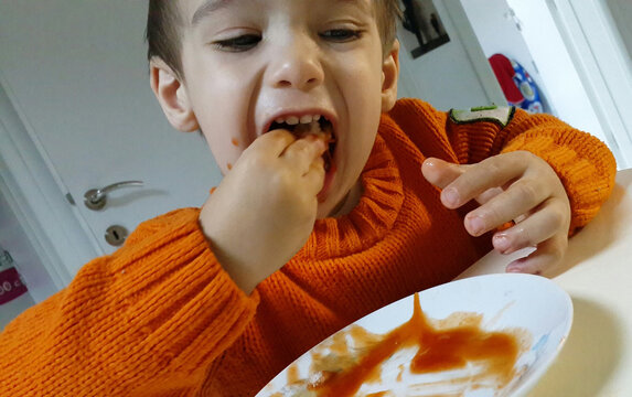 Hungry kid stuffing food in his mouth