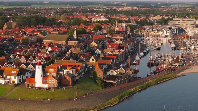 Charm of Urk's coastal town with its iconic lighthouse, traditional houses, and bustling harbor activities on a sunny day