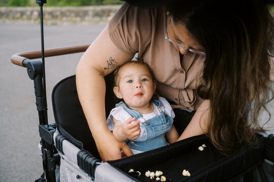 mother placing her toddler daughter into stroller