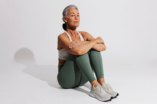 Senior sportswoman resting after workout session on white background