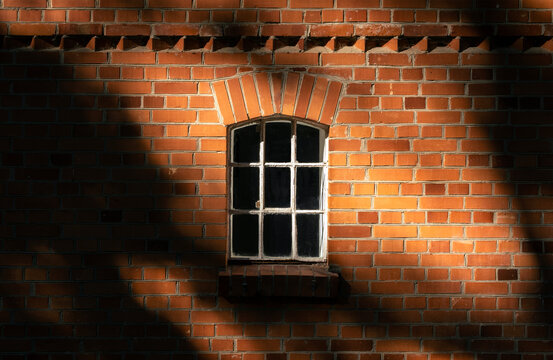 High contrast deep shadows old window in a brick wall