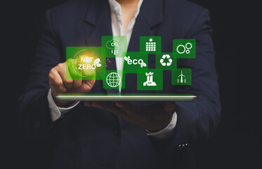 Businessman using tablet with net zero and eco icons. concept of sustainability and green...