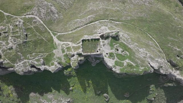 Spectacular descent with a drone in a top-down view of the ruins of the Oreja castle, visualizing the enclave with its access roads, its keep, the gorge and demolished structures, very cinematic