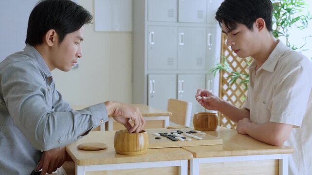 Asian young men playing board game Go during competition in community. 