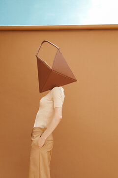 Surreal Portrait of Person with Bag on Head Against Minimal Back