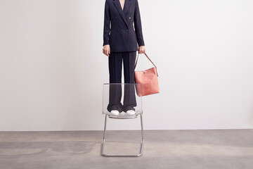 Businesswoman Standing on Chair with Stylish Handbag