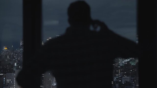 Man talking on the phone. silhouette of angry and upset guy. yelling, shouting and waving his hands. Manhattan skyline view at night. businessman fighting arguing. speaking with someone on smartphone.