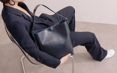 Elegant Woman Holding Crocodile Leather Handbag in Stylish Outfi