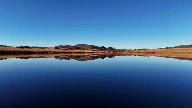 Low level flying video over a lake in a serene landscape, captured with a drone on a windless day