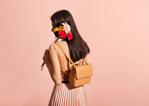 Fashionable Woman Holding Flowers Against Pink Background