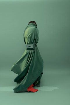 Person Draped in Green Fabric with Red Boots