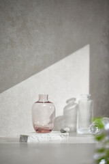 A gray-toned tile background with various props with sunlight coming through the window.