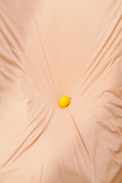 Single Yellow Lemon Resting on a Beige Fabric Surface