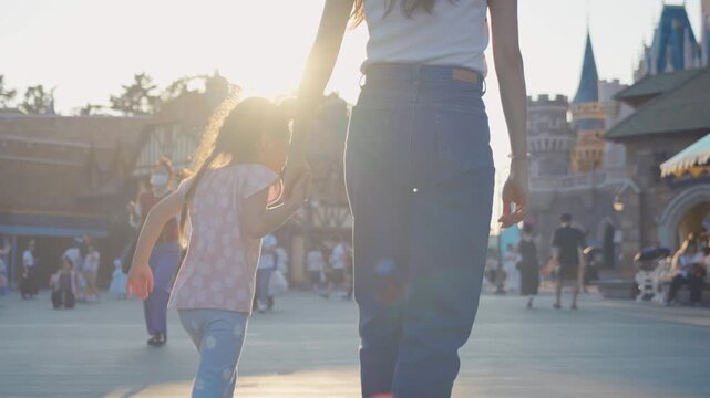 Asian mother and adorable kid daughter walking at the theme park. 