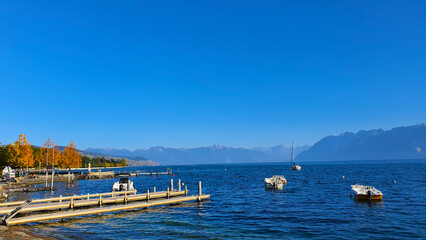 Fototapeta premium Boats on Lake Geneva, Lausanne, Switzerland in autumn, with deep blue water and sky.
