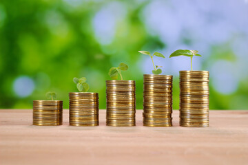 Upward financial growth Stack of golden money coin with growing leaves on wooden desk against nature background. concept of investment growth, rich wealthy and saving money