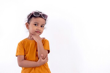 Portrait of a little Asian girl with glasses on her head posing with her hand under chin