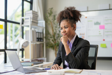 Stressed businesswoman looking at laptop screen while working on a difficult task in a modern office
