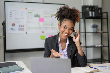 Businesswoman is smiling while talking on the phone and gesturing with her hand in a modern office