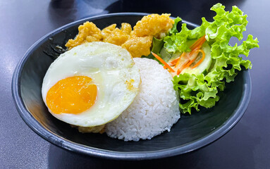 rice bowl with salted fried dory fish and egg served with salad in black bowl