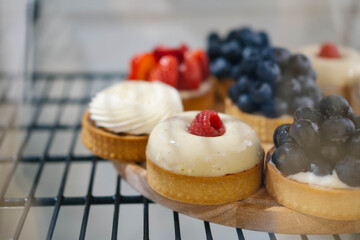 Delicious cake with white vanilla butter cream, nuts. Sweet chocolate dessert with berries on display in a cafe. Handmade pastry shop with showcase. 