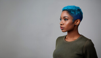 Beautiful portrait of black woman with blue hair on grey background. Confident, smiling.