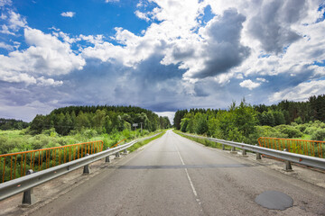A long, empty road with a few trees in the background