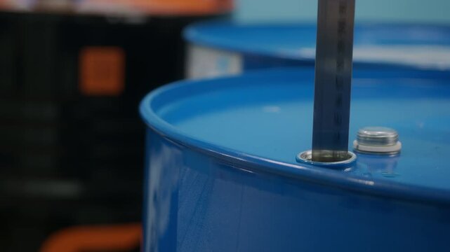 Video. The measuring ruler is lowered into the neck with a barrel of engine oil. Liquid flows from a metal ruler. Close-up.