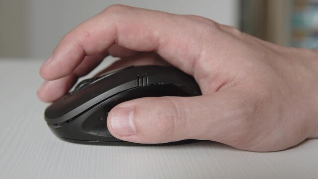 European man clicks his finger on right button of wireless black mouse close up. Control of computer peripherals and multiple selection of actions on pc.